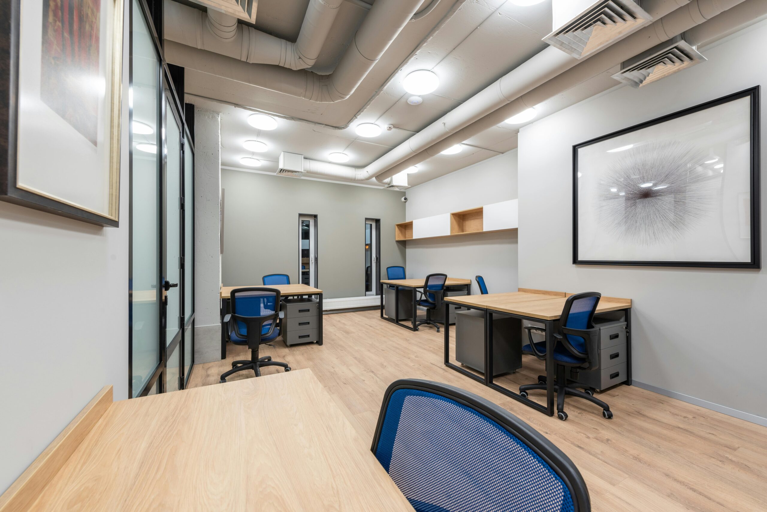 Contemporary office interior with desks, chairs, and abstract art. Ideal for business settings.